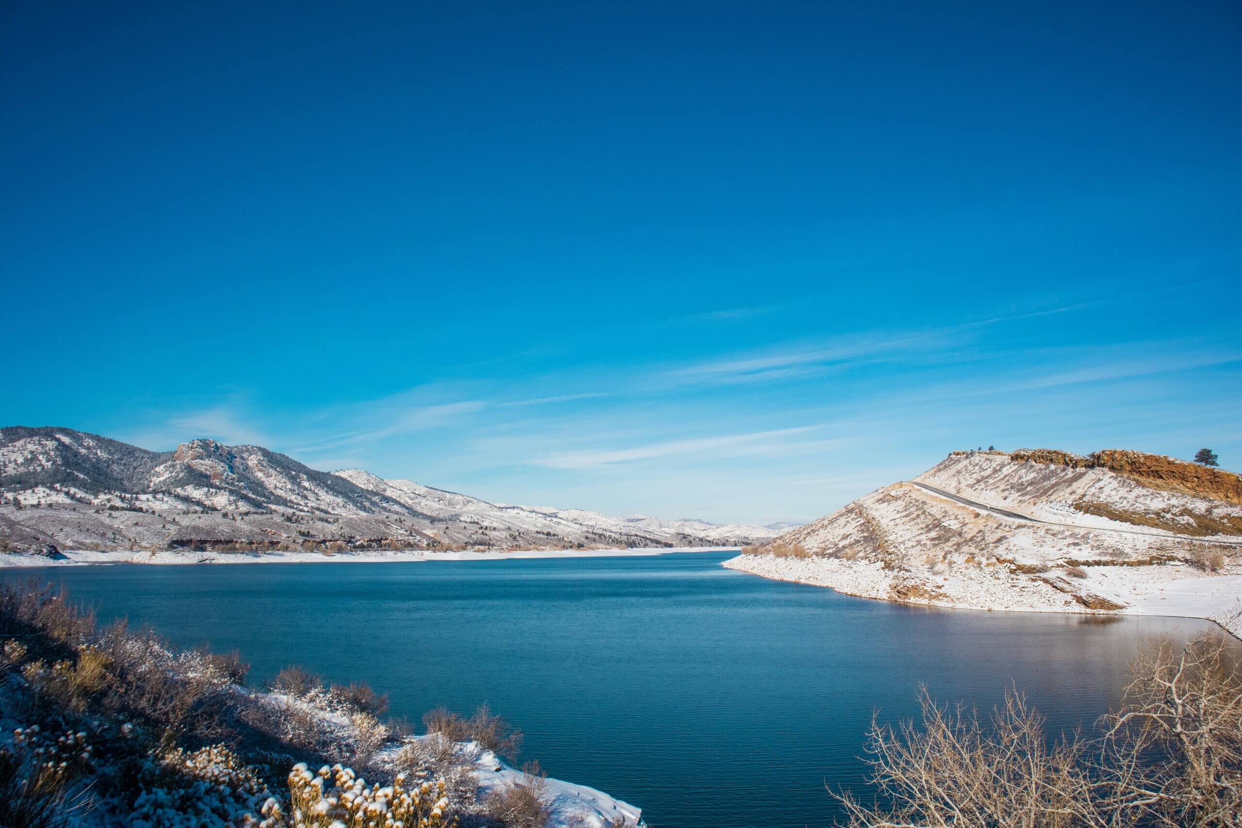 An expansive view of Horsetooth Reservoir with the shoreline lightly dusted in snow