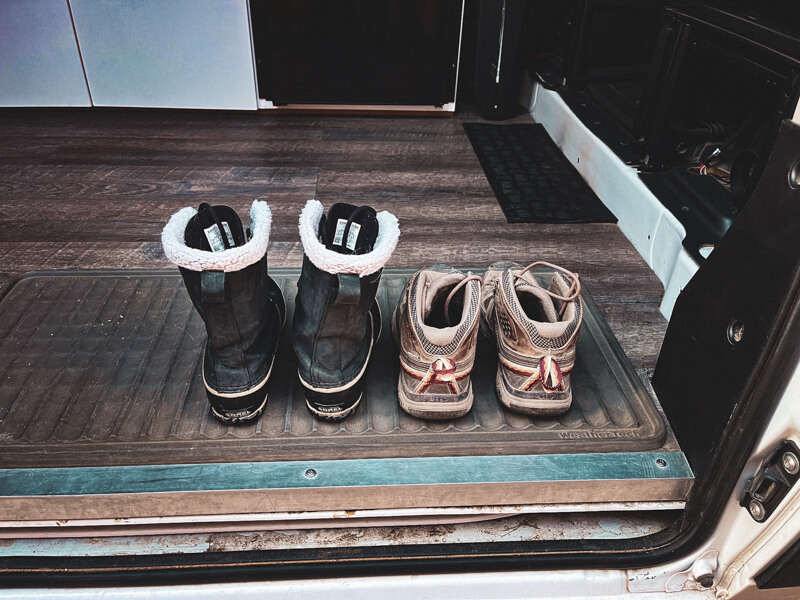 Winter boots resting on a rubber boot mat inside a camper van