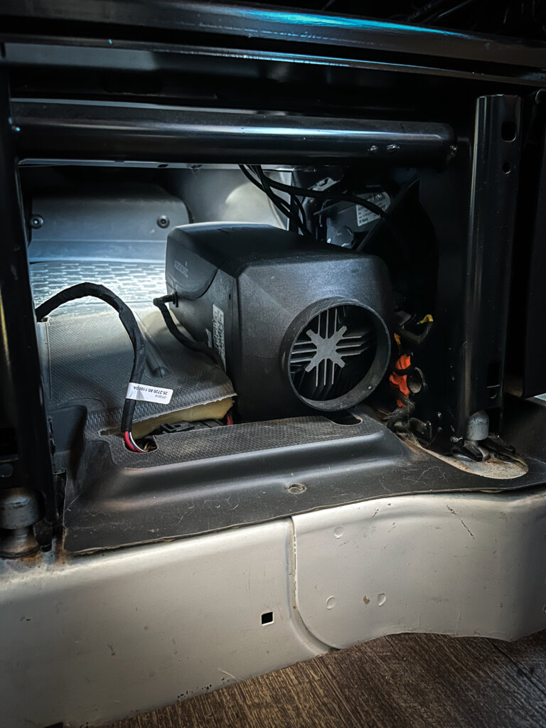 An Espar heating system installed under the passenger seat in a camper van